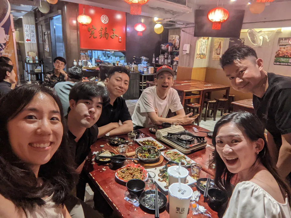 Friends smiling for a selfie around a shared dinner table after Launch Station Prezzy Day