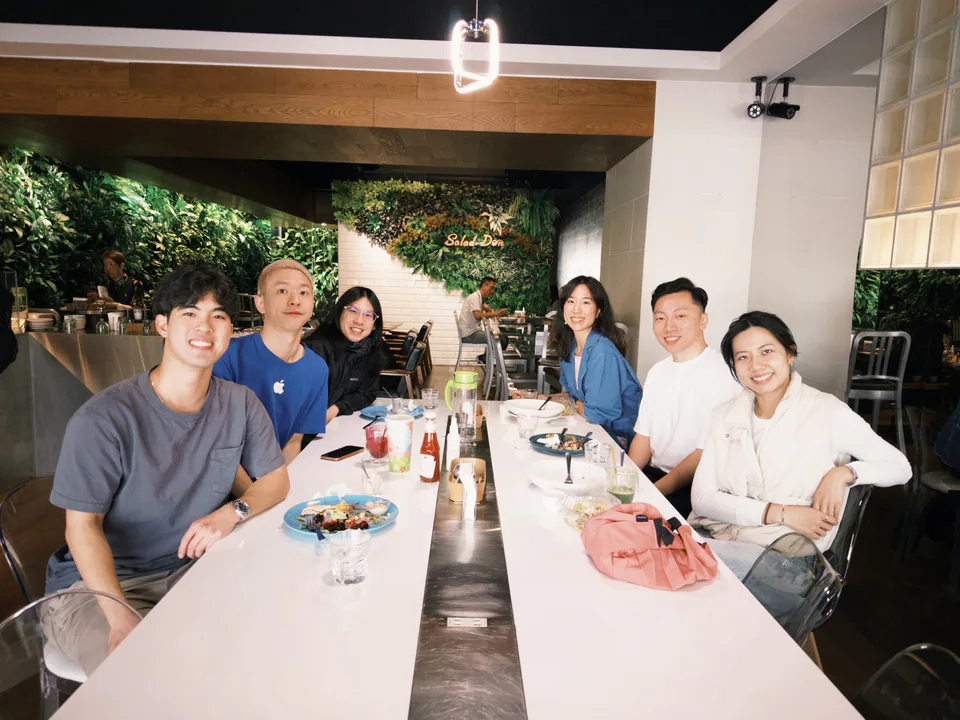 Six people smiling around a restaurant table during a Launch Station community lunch